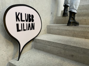 Tuffa skor går förbi en skylt "Klubb Lilian" i en betongtrappa