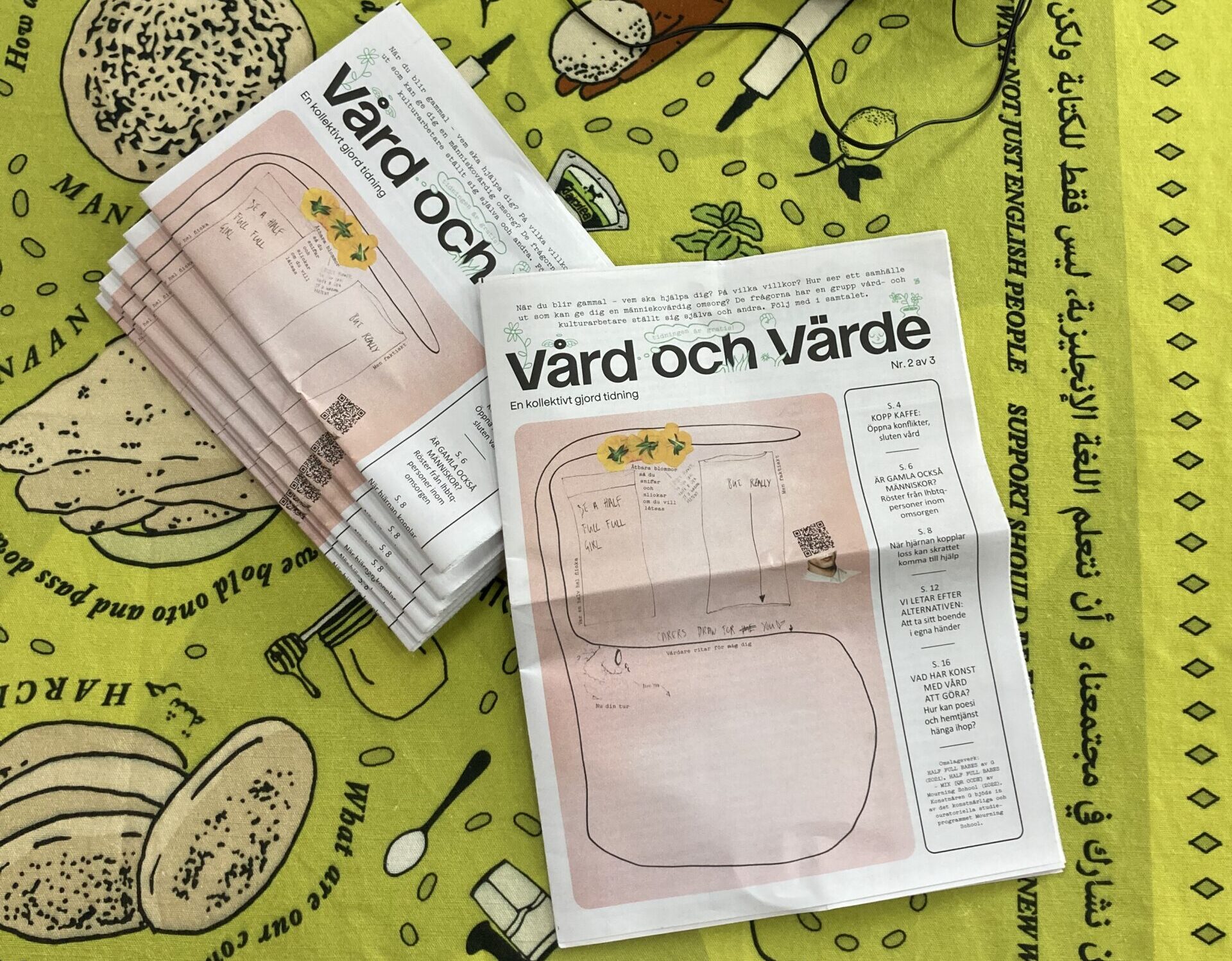 Två tidningar och hörlurar ligger på en grön filt