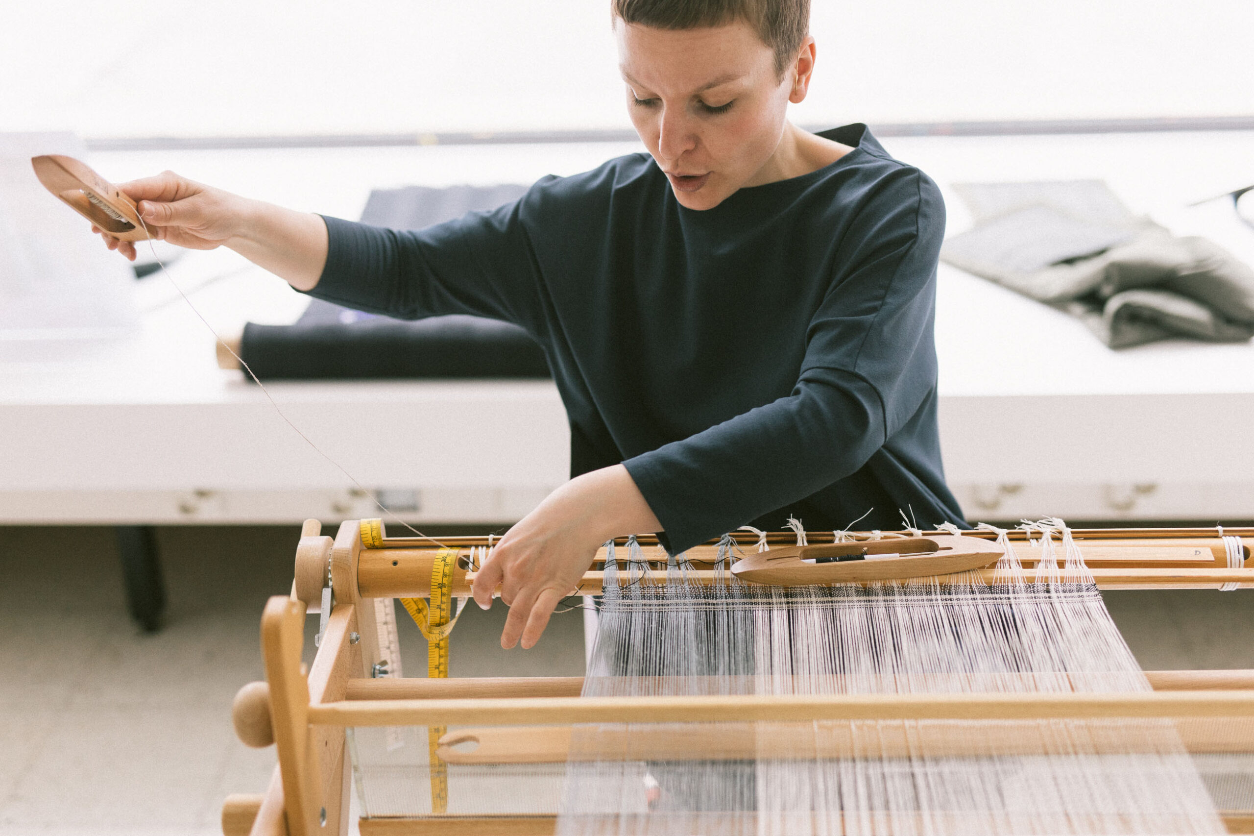 En kvinna sitter vid en vävram